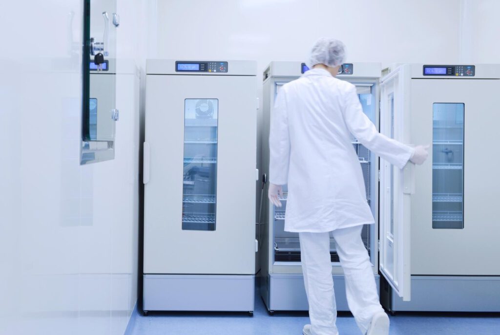 Person in the white lab coat is looking into the medical cabinet 