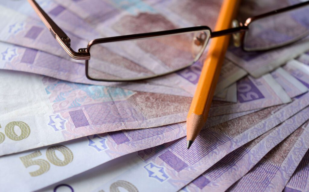 Ukrainian hryvnia, pencil, and glasses